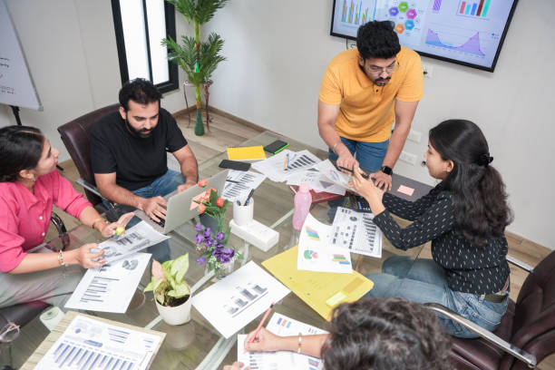 Team around a table with charts, documents, and a screen of data